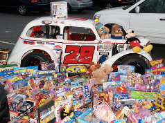 A race car loaded with stuffed animals beside boxed toys