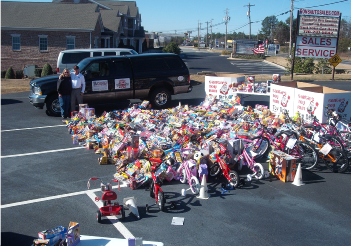 Bikes and toys lined up across a parking lot beside a pickup