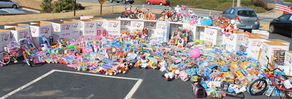 A long row of Toy Drive boxes and toys in a parking lot