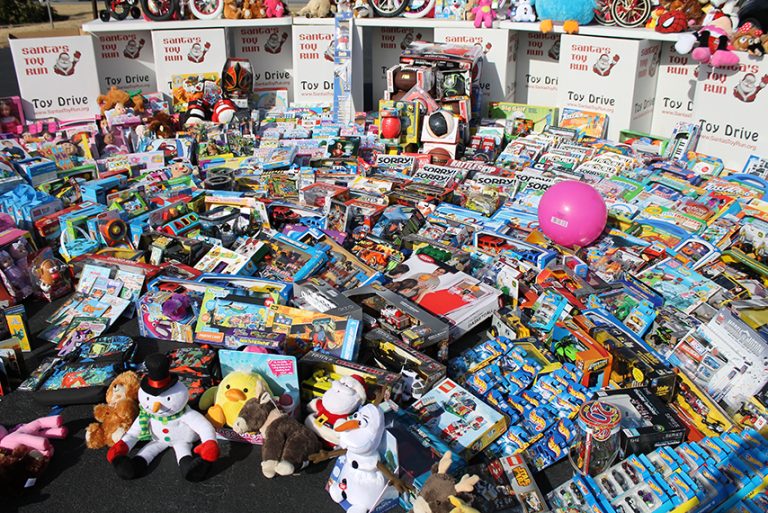 Stuffed animals, a pink ball and boxed toys piled on the pavement