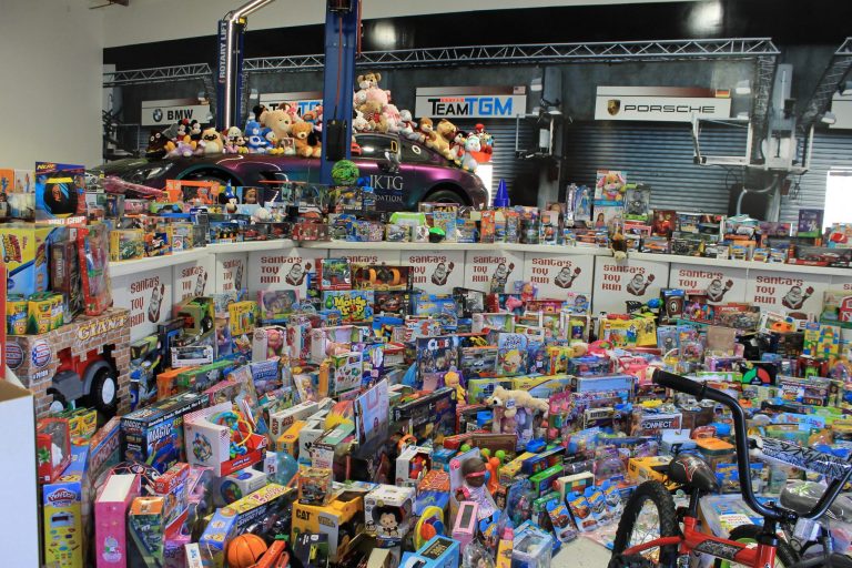 Donated toys stacked across a showroom under Team GM banners